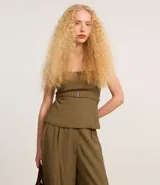Blusa sin breteles color verde militar, confeccionada en crepé, con cierre de cremallera en la espalda y cinturón elástico con hebilla negra.