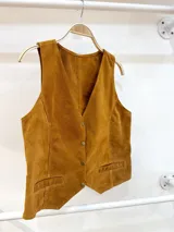 Chaleco marrón de gamuza con cuello en V, cierre con botones y bolsillos frontales con detalle de costuras. Corte recto.