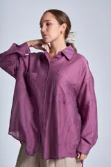 Camisa negra de tela traslúcida con cuello clásico, cierre frontal con botones y dos bolsillos de parche en el pecho.