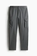 Pantalón cargo gris oscuro de piqué, corte slim fit, con bolsillos laterales con solapa y botón a presión, bolsillos al bies y bolsillos insertados atrás. Cintura clásica con cordón ajustable oculto y elástico revestido atrás.
