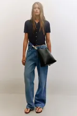 Bolso de hombro formato saca de color negro, con cierre mediante clip metálico y un compartimento interior extraíble con cremallera. Incluye un asa de hombro con diseño estampado y detalles metálicos dorados.