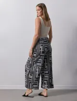 Pantalón ancho estilo palazzo, de seda fría plisada con estampado geométrico en negro, blanco y beige. Tiene pretina ancha elastizada y largo crop.