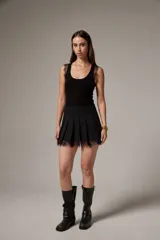 Minifalda negra de algodón con diseño plisado y detalle de encaje transparente en el ruedo.