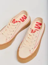 Championes bajos color crema con pespuntes rojos, capellada de tela canvas y plataforma de goma color caramelo de 4 cm de altura.