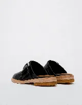 Mules de cuero negro con hebilla plateada y suela color madera.