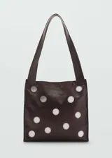 Bolso marrón de cuero con apliques circulares metálicos.