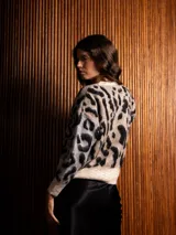 Buzo de tejido de punto con textura suave, diseño de estampado animal print en tonos beige, gris y negro, cuello redondo y mangas largas.