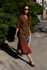 Vestido midi de corte recto, color marrón en la parte superior y marrón rojizo en el inferior con detalle de franjas horizontales superpuestas. Cuenta con escote en V y mangas cortas holgadas.