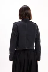 Chaqueta de jean estilo napoleónico color negro, con cuello mao, hombreras y filas dobles de botones metálicos grabados.