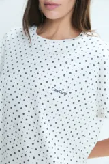 Pijama de dos piezas compuesto por una remera de manga corta con cuello redondo y un pantalón largo de corte recto, ambos con estampado de lunares pequeños.