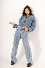 Pantalón de jean estilo straight con tiro medio, confeccionado en denim de lavado claro. Presenta costuras decorativas verticales que recorren el frente de las piernas y aberturas en el ruedo.