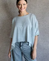 Remera de corte oversize y estilo crop, confeccionada en lanilla de textura suave. Presenta cuello redondo y mangas cortas con caída holgada.