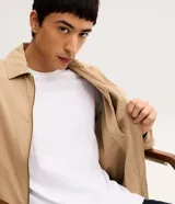 Campera bomber masculina de sarga color beige, con cuello inglés, cierre frontal de cremallera, bolsillos y elásticos en puños y cintura.