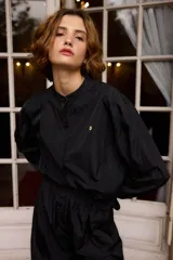 Camisa de nylon color bordó, de corte holgado y diseño minimalista con mangas largas abullonadas y puños elásticos.