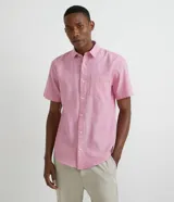 Camisa de manga corta confeccionada en mezcla de lino y algodón, con cuello inglés, cierre frontal de botones y bolsillo en el pecho. Presenta un corte comfort holgado y diseño liso.