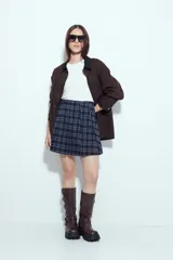 Minifalda tableada con estampado de cuadros en tonos oscuros, de corte acampanado y estilo colegial.