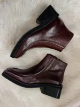Botas cortas color bordó con punta cuadrada, suela negra y cierre lateral.