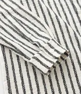 Camisa de manga larga con cuello inglés y cierre frontal de botones. Presenta un diseño de rayas verticales en tonos neutros, confeccionada en tejido de poliéster con caída estructurada y corte comfort.