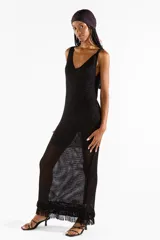 Vestido largo negro de punto abierto con sutil brillo de lúrex, escote en V y detalles de flecos en el ruedo.
