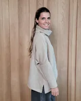 Polera de tejido suave con textura acanalada, cuello alto tipo tortuga, mangas largas y corte holgado con aberturas laterales en el ruedo.