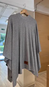 Ruana de tejido de punto fino en color beige, con diseño abierto y caída fluida.