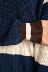 Sweater oversize de tejido de punto con diseño de rayas horizontales anchas en color beige y azul marino, cuello redondo marrón y puños y dobladillo en marrón con líneas beige y blancas.