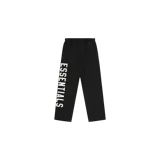 Pantalón de jogging Fear of God Essentials Fleece Relaxed Sweatpant en color negro, con diseño relajado, cintura elástica con cordones ajustables y el logotipo "ESSENTIALS" estampado verticalmente en contraste sobre la pierna derecha.