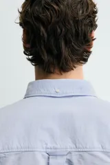 Camisa de corte regular fit confeccionada en tejido de algodón tipo Oxford. Presenta cuello abotonado, manga larga con puños abotonados, bolsillo frontal en el pecho y cierre de botonadura central.
