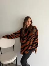 Buzo de peluche con estampado animal print tipo tigre en tonos marrón y negro, de corte oversize y cuello redondo.