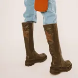 Botas de caña alta de cuero color marrón oscuro, con suela track y detalle de estrella de cuero con textura de piel de serpiente en el lateral exterior. Cierre con cremallera en el lateral interior.