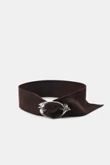 Cinturón ancho de ante color marrón con hebilla metálica plateada de diseño orgánico y forma ovalada.