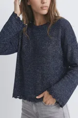 Sweater de punto en color azul con destellos de lurex, cuello redondo, mangas largas acampanadas y terminaciones con borde festoneado.