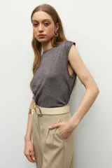 Top sin mangas color beige, de cuello redondo y corte ajustado. Presenta frunces en los laterales.