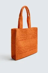Bolso tipo shopper de diseño trenzado en color tostado, con estructura rectangular, dos asas de mano y compartimento principal abierto.