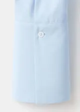 Camisa celeste de algodón y lyocell, con cuello camisero, mangas largas con puños anchos, cierre frontal con botones y sutil bordado floral en el pecho.