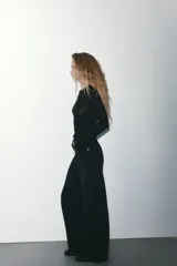 Jeans de mezclilla en color negro gastado, tiro alto, diseño de cinco bolsillos y corte de pierna ancha extra larga. Cuenta con cierre frontal de cremallera y botón metálico.