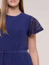 Vestido corto azul de seda fría elastizada, con mangas cortas de encaje calado, lazo para ajustar en la cintura y ruedo con volado plisado.