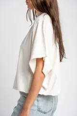 Remera oversize de algodón blanco crudo, con cuello redondo y mangas cortas anchas de corte relajado.
