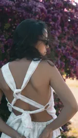 Top halter de broderie blanco con sutil brillo plateado, presenta cuello alto con volados y ruedo con volado amplio. Diseño sin mangas, femenino y ligero.