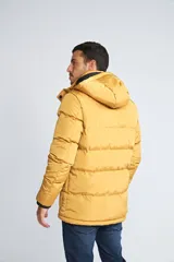 Campera puffer color mostaza con capucha, cierre frontal con botones y bolsillos laterales. Cuenta con logo de la marca en el pecho.