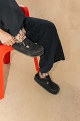 Zapato tipo zueco de cuero color beige, con diseño tejido artesanal en todo el contorno y ajuste mediante correa con hebilla metálica en el empeine.
