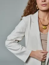 Blazer recto color crudo, de lino, con solapas de muesca, cierre cruzado con doble botonadura, mangas largas y bolsillos con solapa.