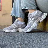 Championes urbanos New Balance modelo 9060, color gris con detalles en tonos más claros. Presentan un diseño robusto con capas superpuestas de gamuza y malla, y una entresuela esculpida con tecnología de amortiguación.