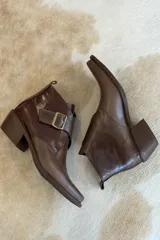 Botin de cuero color bordeaux con diseño de textura combinada, punta cuadrada y hebilla metálica lateral.