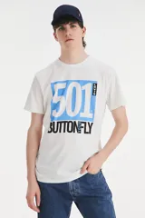 Remera de algodón blanca con cuello redondo y manga corta. Presenta un estampado gráfico frontal con el texto '501' en azul y 'BUTTON YOUR FLY' en negro, junto con el logo de la marca.