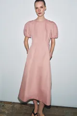 Vestido midi de cuello redondo y manga corta abullonada con terminación elástica. Presenta un diseño de corte evasé con cierre posterior de cremallera oculta.