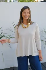 Sweater de tejido de punto en color beige, con cuello redondo, mangas tres cuartos y corte holgado con ruedo ligeramente más largo en la parte posterior.