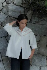 Camisa de algodón color beige con detalles de encaje y broderie en el canesú y las mangas. Presenta cuello camisero, cierre frontal con botones y mangas largas con puños.