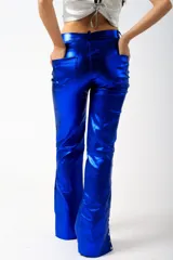 Pantalón de corte flare color verde metalizado, con bolsillos laterales y abertura en los tobillos con botones a presión.