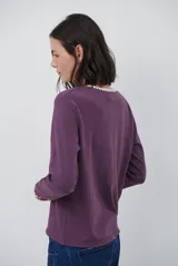 Remera de manga larga en color azul marino, confeccionada en tejido suave. Presenta un delicado detalle de bordado festoneado en color blanco tanto en el cuello redondo como en los puños, aportando un toque distintivo a esta prenda básica.